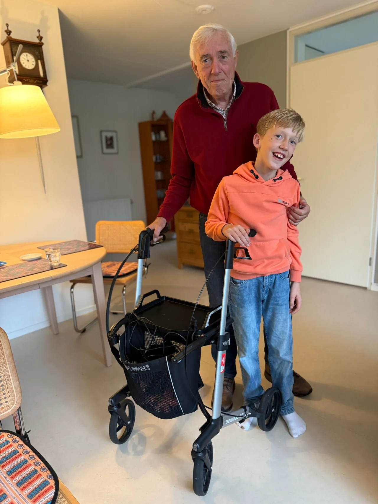 Chris staat naast zijn opa, die zijn arm om hem heen heeft, bij de rollator.